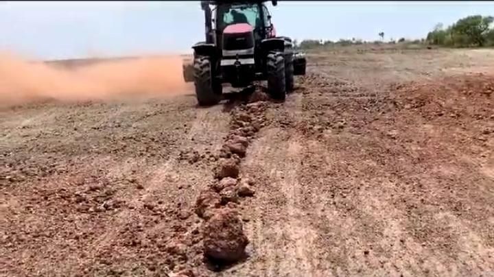 Trator realizando preparo de solo em terreno de solo vermelho