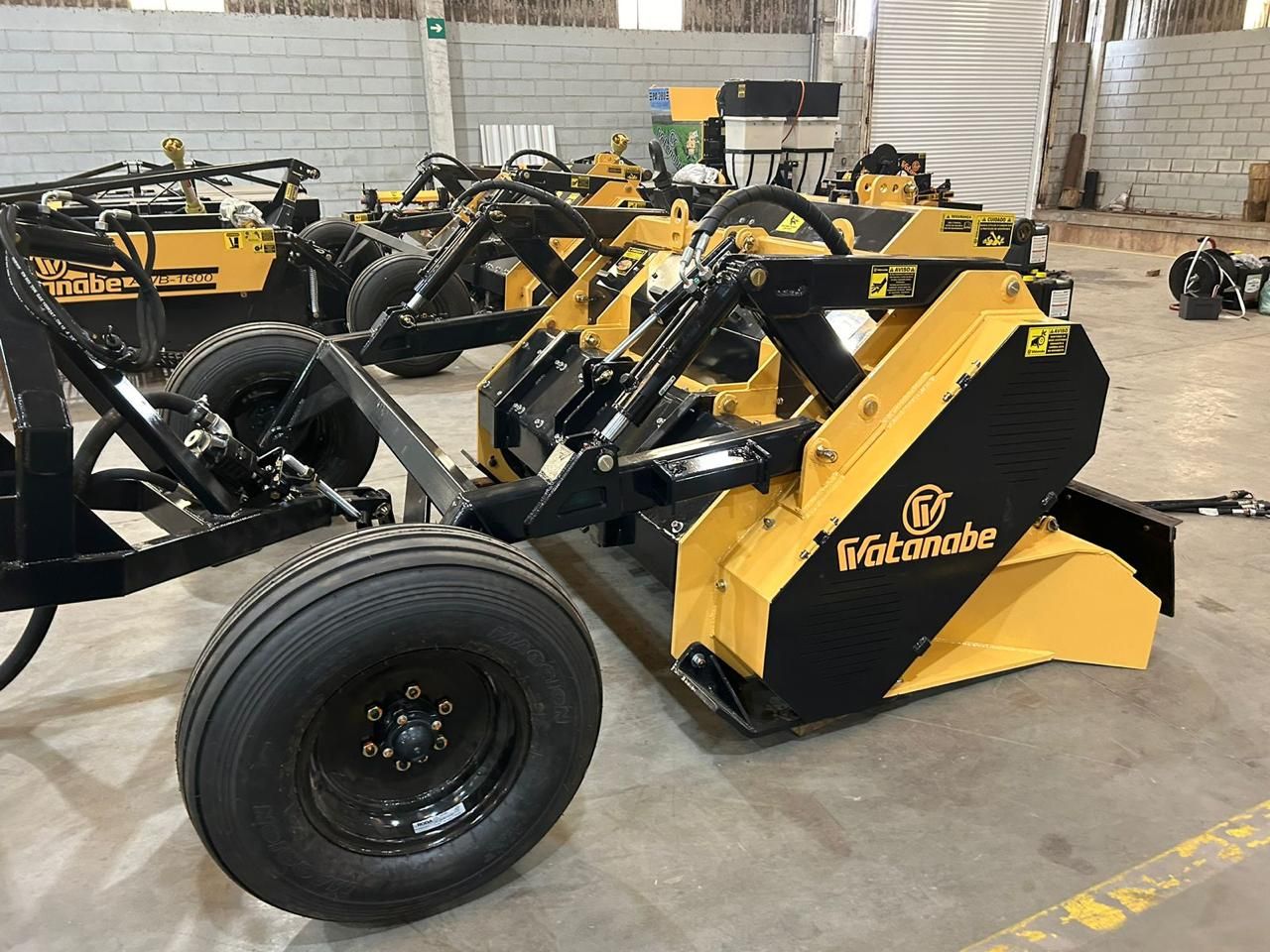 Detalhe de implemento de lâmina amarelo com pneus de transporte