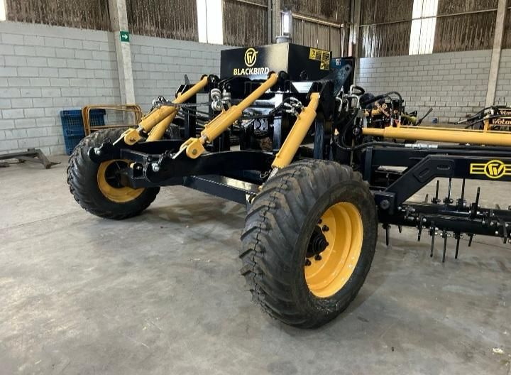 Escarificador de solo preto e amarelo dentro de galpão